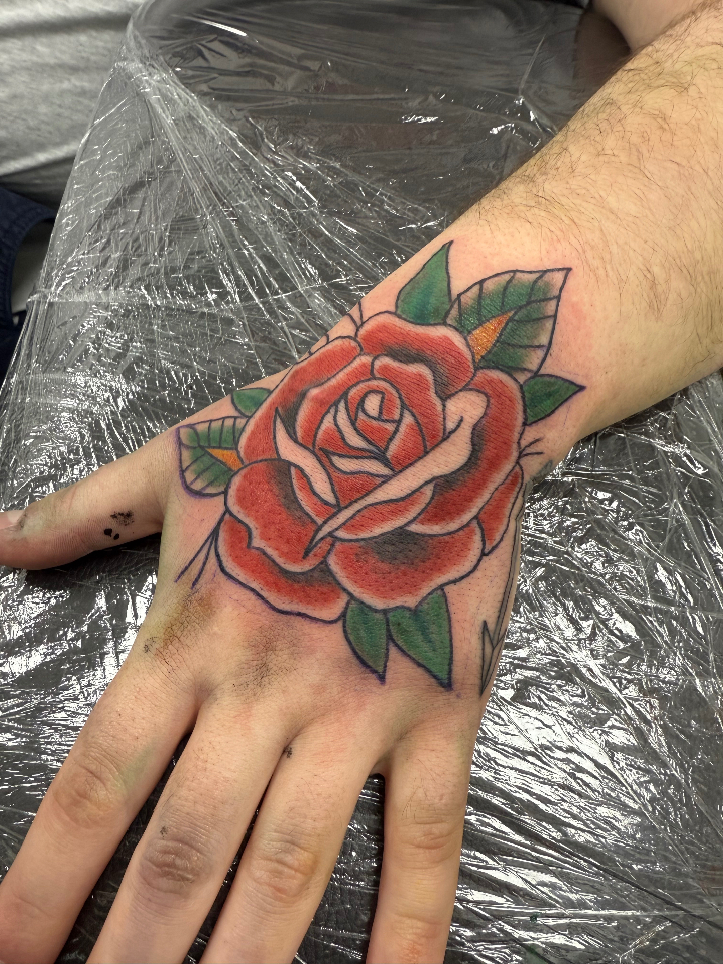 Traditional red rose hand tattoo by Clare