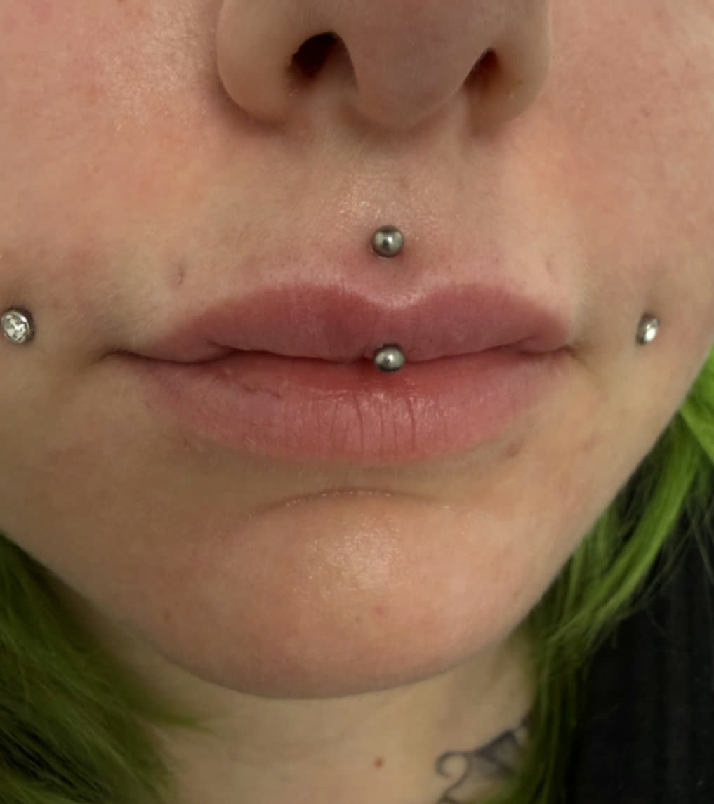Medusa, vertical labret and cheek piercings styled with polished titanium jewellery