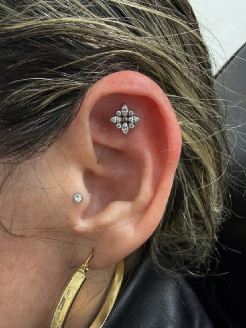 Flat ear piercing with starburst flower jewellery paired with a subtle inner ear stud
