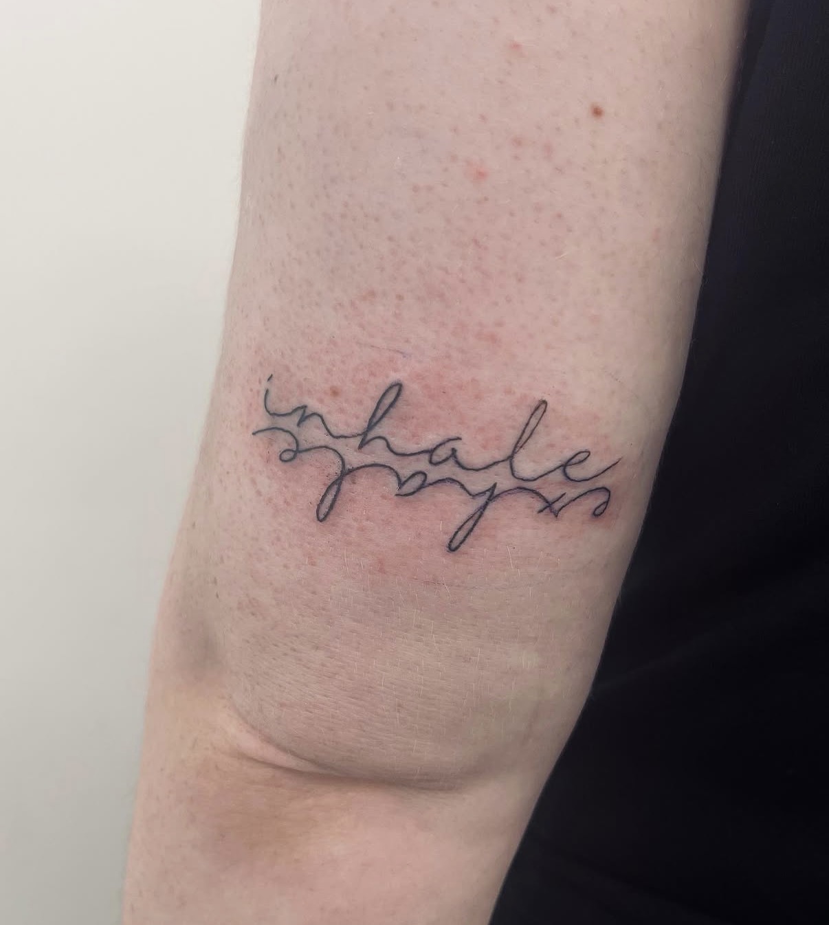 Fine line 'inhale exhale' lettering tattoo by Clare